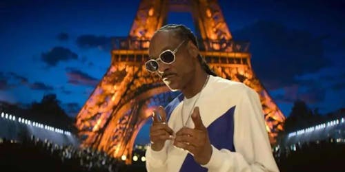 Snoop Dogg holdign a microphone and giving the peace sign with his fingers Snoop Dogg holdign a microphone and giving the peace sign with his fingers