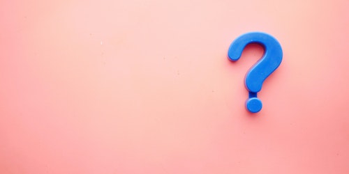 A blue plastic question mark against a pink background
