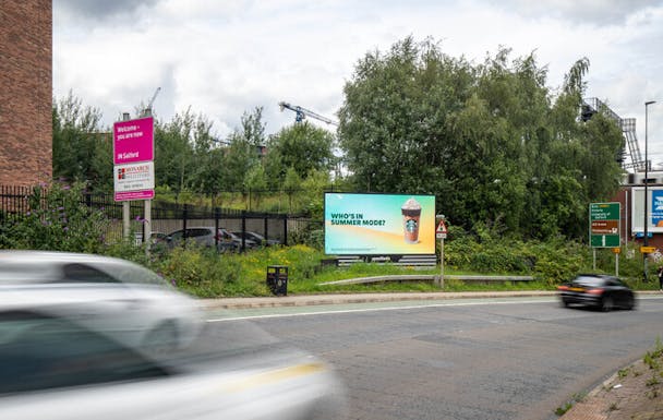 A Starbucks's summer OOH advert on a roadside - The ad reads ‘Who’s in summer mode?'