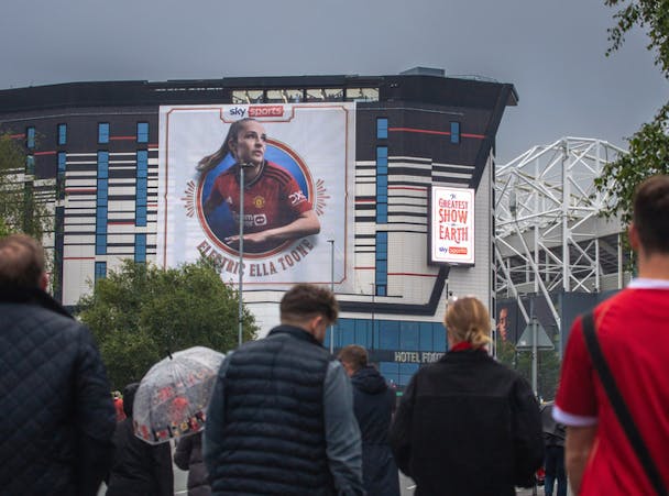 People approach a stadium with a sky sports out of home (OOH) advert on display